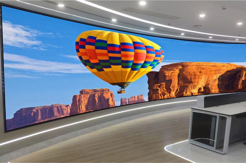 Wide curved indoor LED wall showing a hot-air-balloon scene as one continuous image