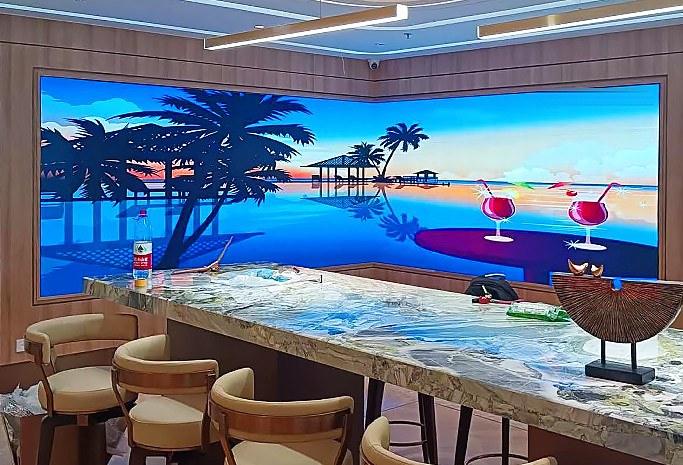 Curved LED wall behind a lounge bar showing a tropical sunset